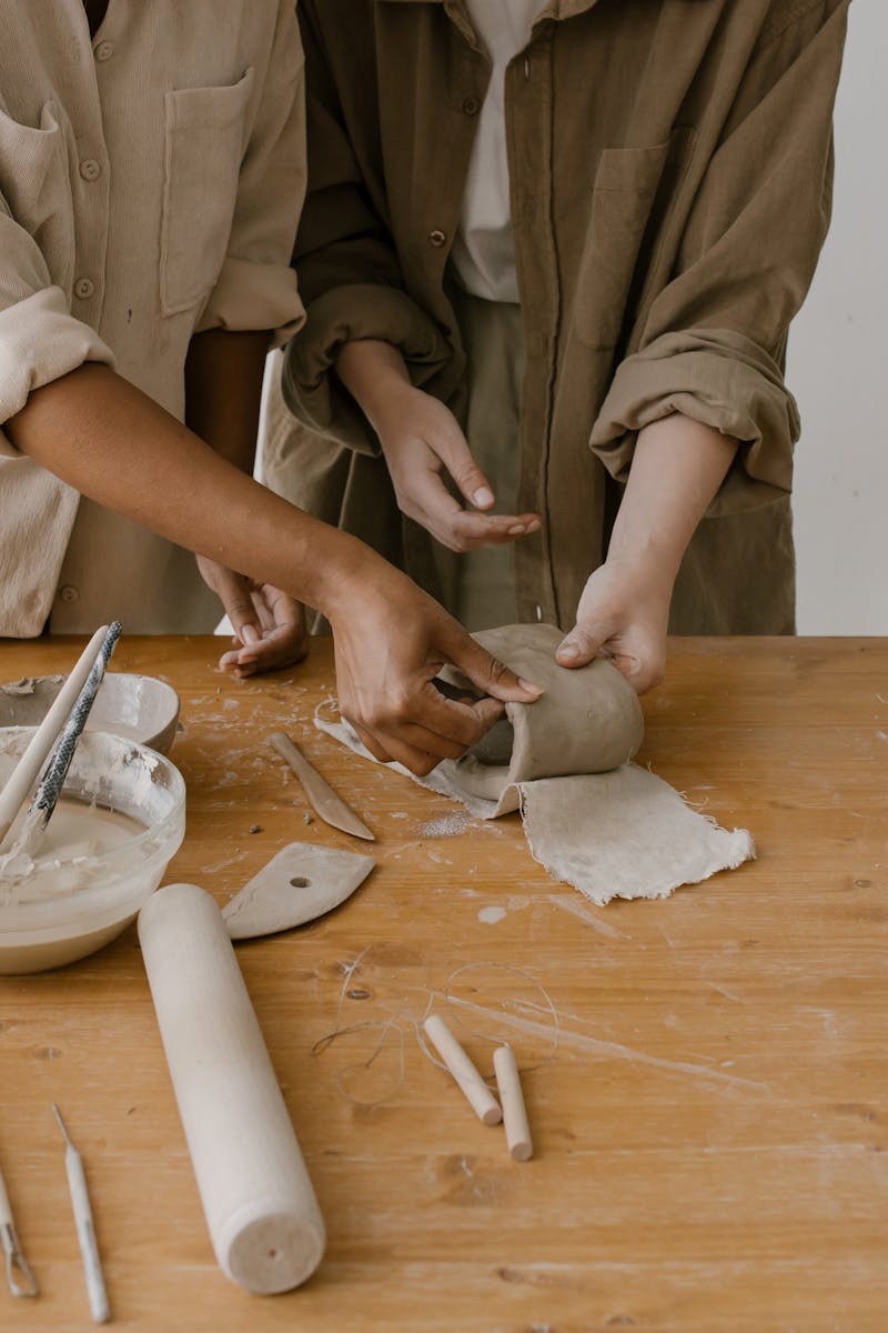 Two people handcrafting pottery, showing detailed craftsmanship and creativity.
