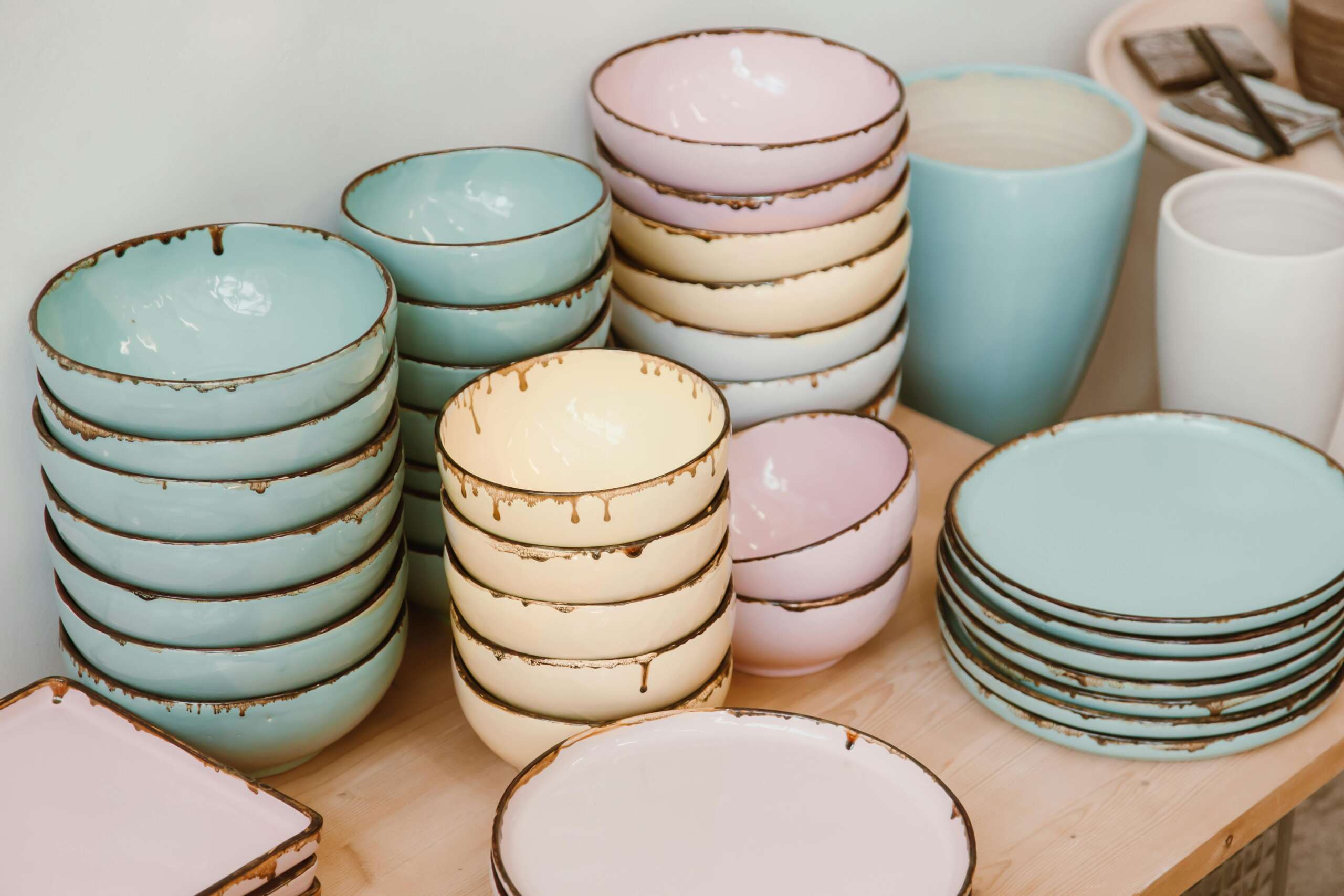 Pastel-colored ceramic bowls and plates neatly stacked on a wooden surface, showcasing rustic elegance.